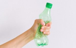 Crop unrecognizable woman squashing plastic bottle